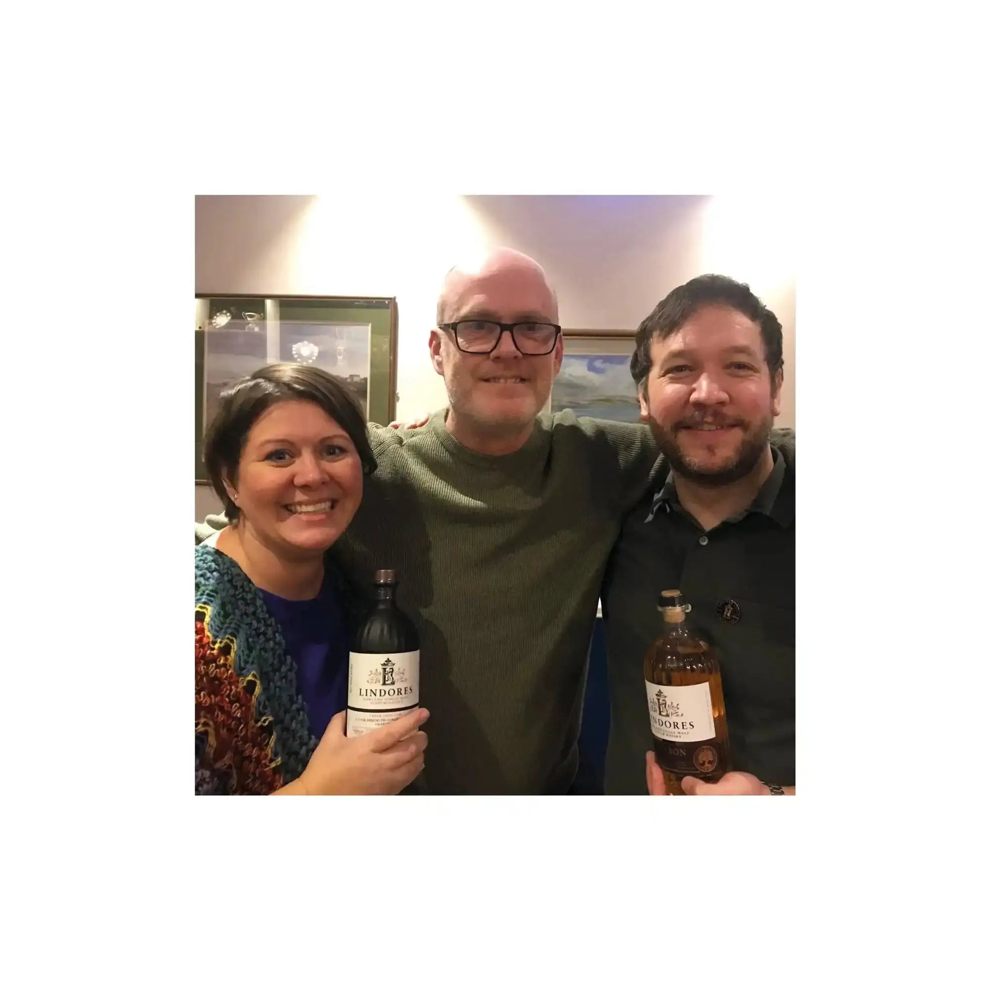 Three people holding liquor bottles.