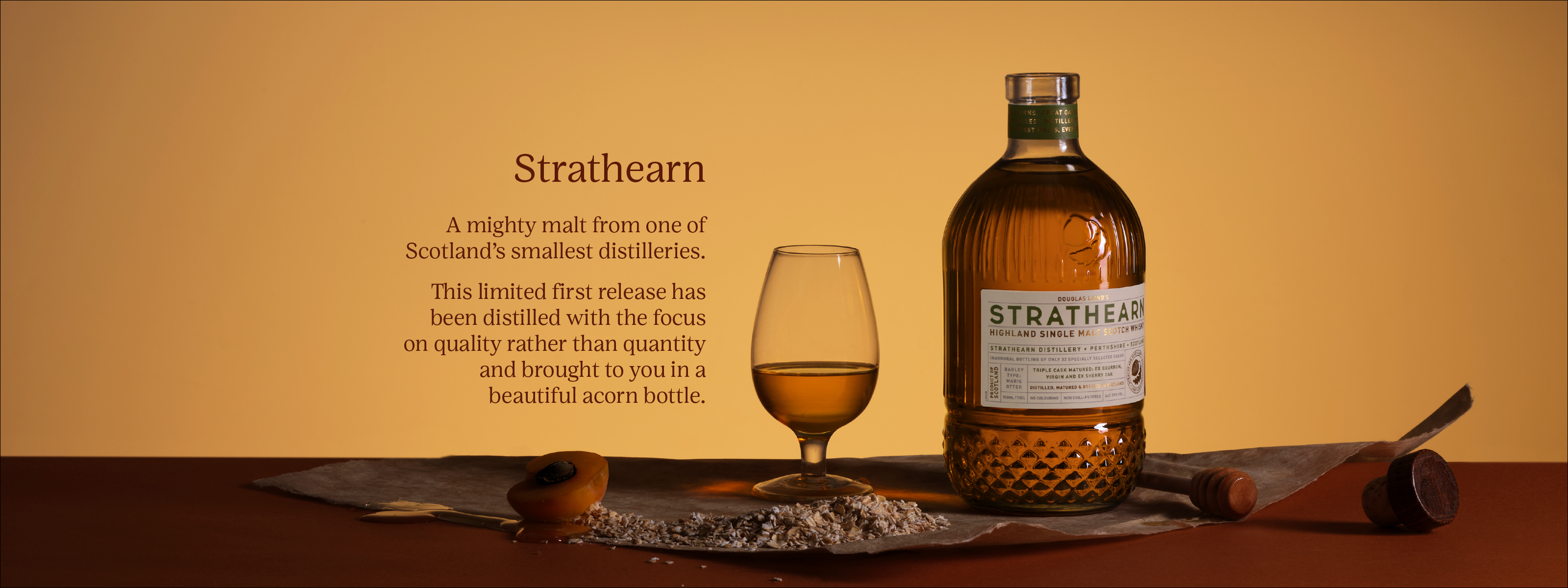 Photo of a bottle of Strathearn on a golden background with text - Strathearn A mighty malt from one of Scotland’s smallest distilleries. This limited first release has been distilled with the focus on quality rather than quantity and brought to you in a beautiful acorn bottle.